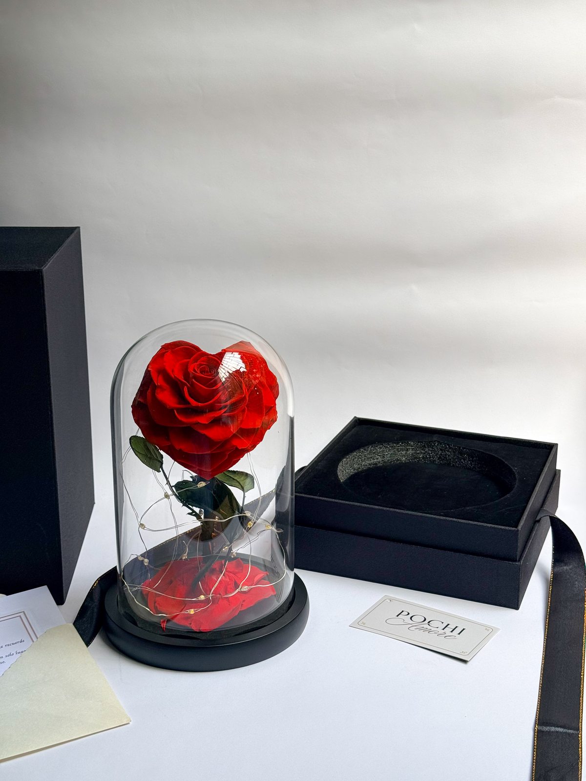 Rosa Eterna Corazón roja en cúpula de vidrio junto a sobre y tarjeta