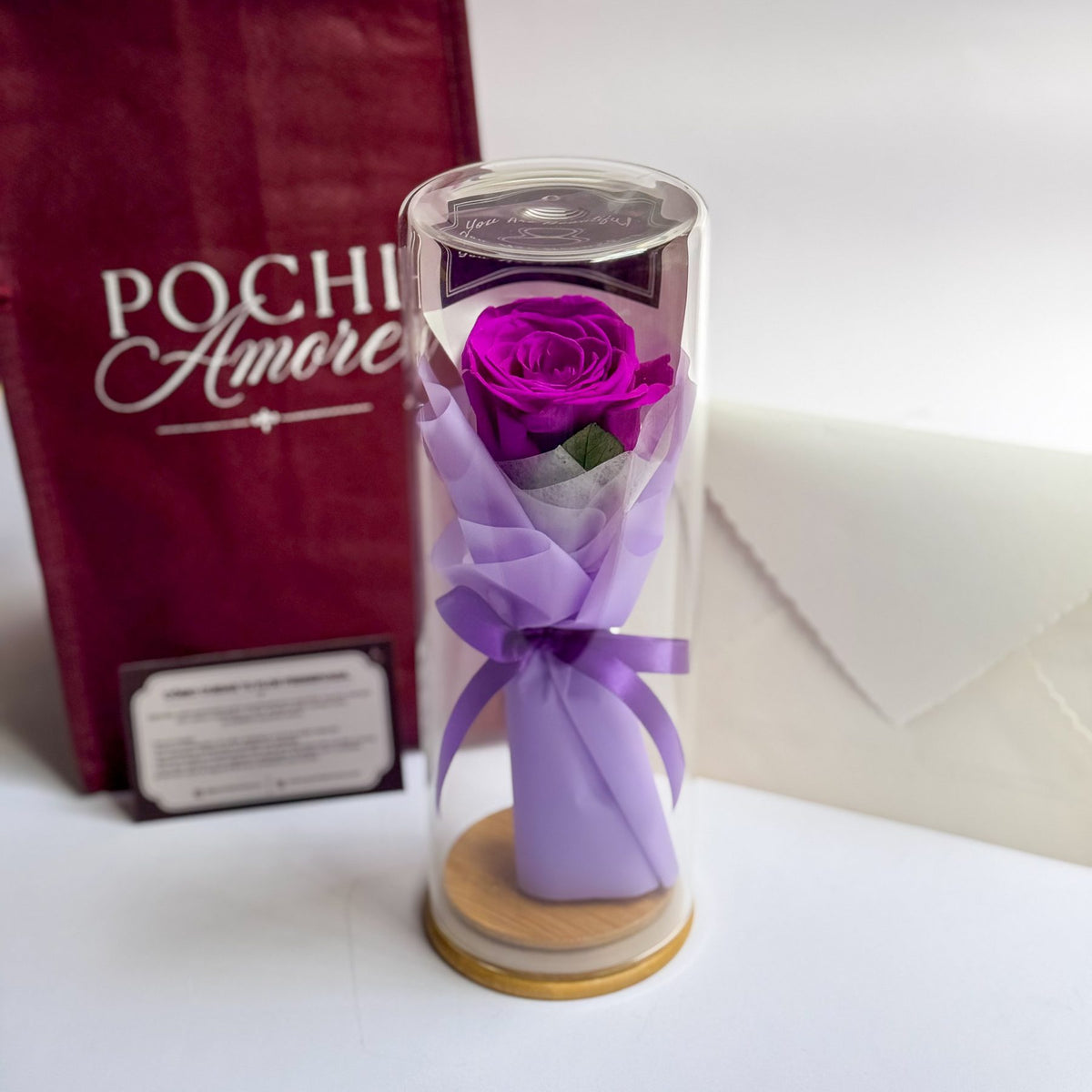 Rosa Eterna Elegance morada en tubo de vidrio con tarjeta de cuidados