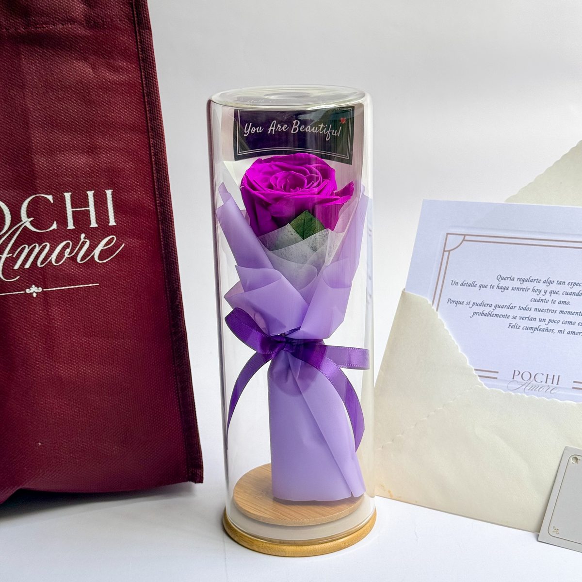 Rosa Eterna Elegance morada en tubo de vidrio junto a sobre y tarjeta